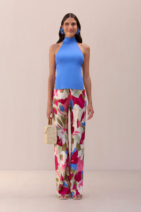 Woman wearing a periwinkle, knit top that features a fold over mock neck paired with floral printed pants. 