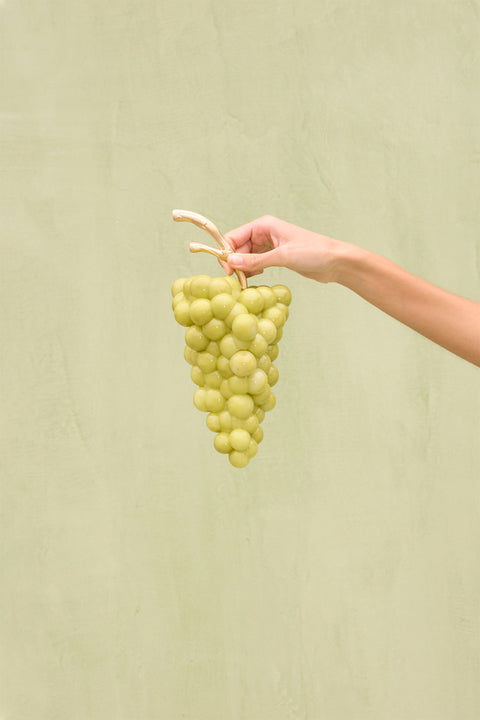 A light green acrylic clutch that resembles a bunch of grapes with a gold toned stem. 