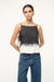 Close up of a woman wearing a black and white dip dye patterned boxy tank top that is open on the sides with ties, paired with jeans. 