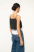 Back view of a woman wearing a black and white body tank top that is open on the sides, paired with jeans. 