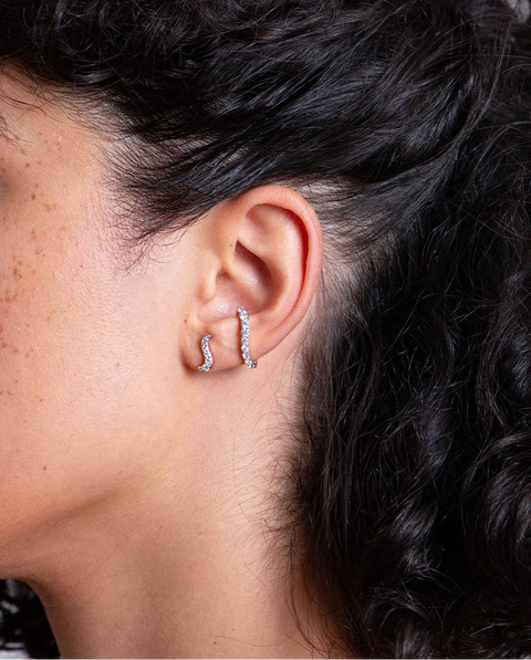 Woman's ear wearing the yellow gold and diamond ear cuff earring and diamond earring stud.