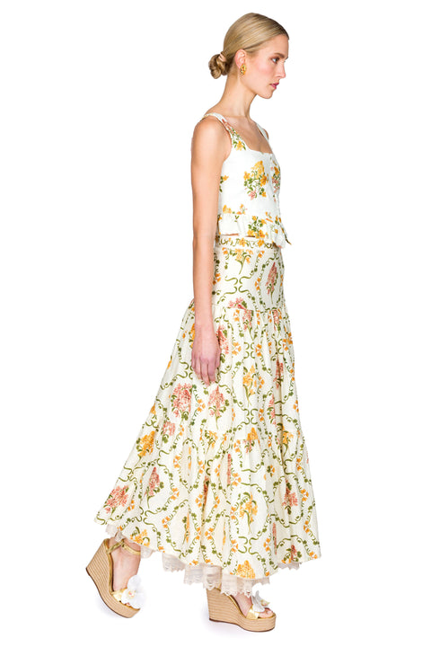 Woman wearing a yellow and pink floral cropped tank and maxi skirt on a white background from the side