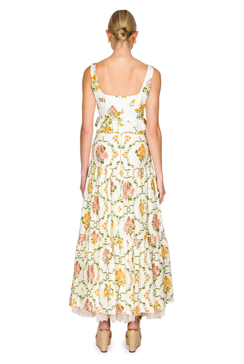 Woman wearing a yellow and pink floral cropped tank and maxi skirt on a white background from the back
