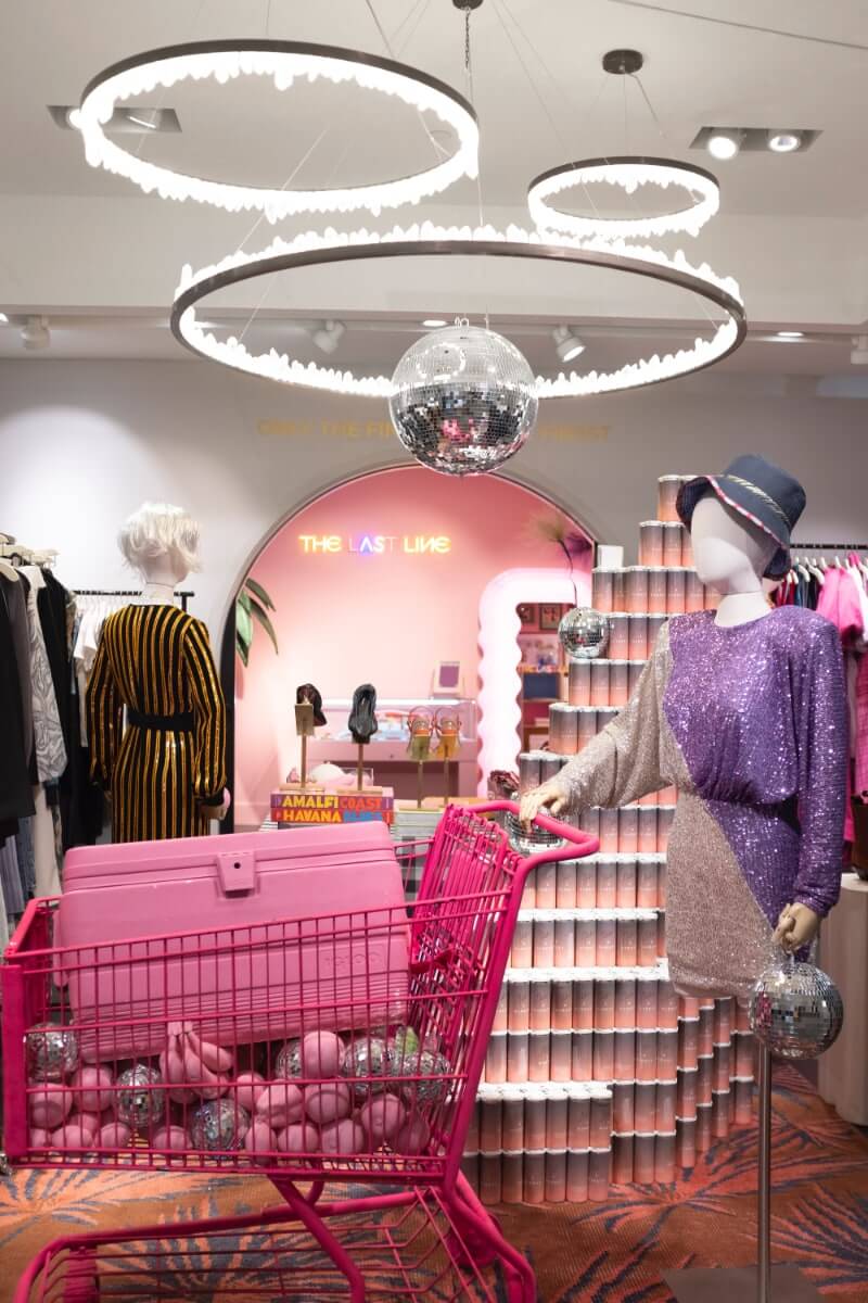 Pink shopping cart display with mannequin in sparking purple dress