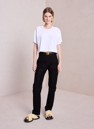 Model facing the camera in the white Oliver Tee paired with black pants