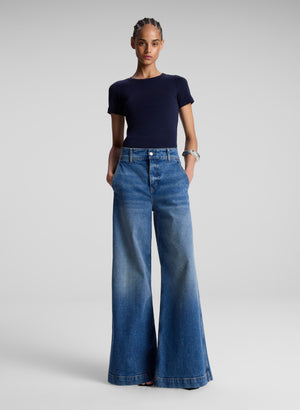 Women in a navy blue t-shirt and wide leg jeans.