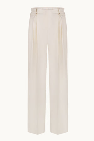 Ivory pants with side pleats and decorative button detailing at the waist.