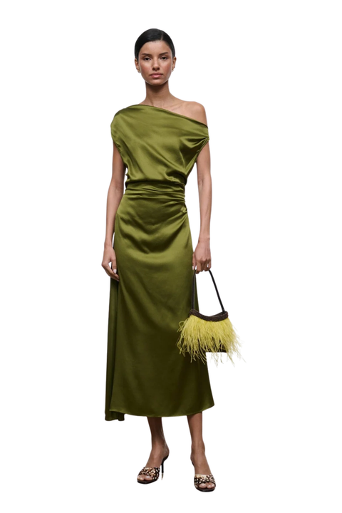 A model wearing a draped olive green one-shoulder midi dress with a matching feather-trimmed handbag and leopard-print heels, set against a plain white background.
