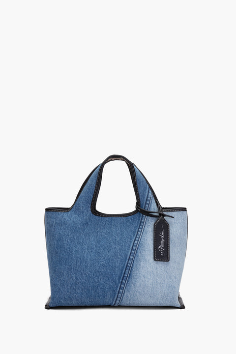 Front view of mini denim tote with black leather trim and black logo leather luggage tag.