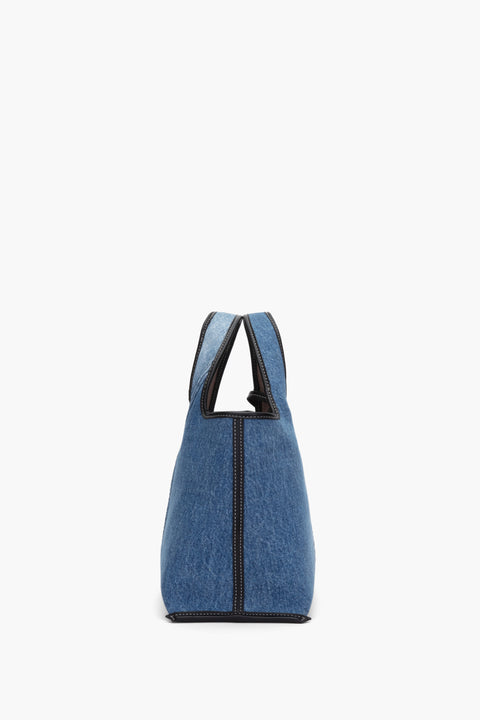 Side view of the mini denim tote with black leather trim.