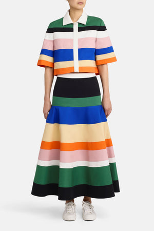 Full body view of a model wearing the multicolor stripe midi skirt with a matching top and facing the camera