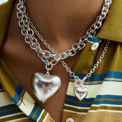 Up close of large pendant heart necklace styled with the smaller version.