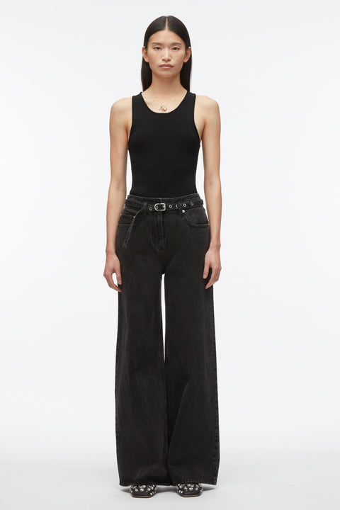 Woman wears compact knit tank top in black with black belted pants.