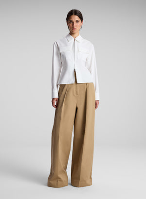 Women wears white zipper accented top with front pockets.