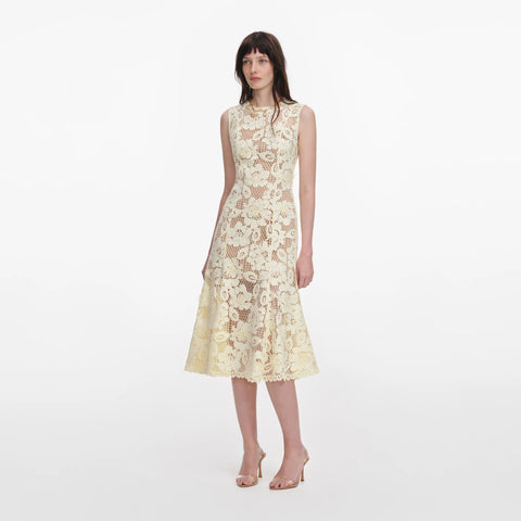 Woman facing left wearing a floral lace dress on a white background