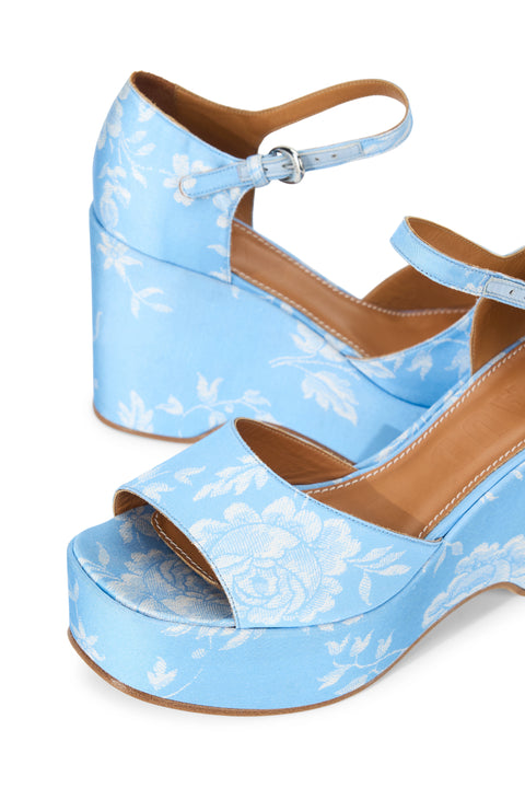 Detail shot of a pair of light blue wedge heels with white floral print