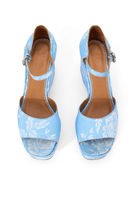 Above view of a pair of light blue wedge heels with white floral print