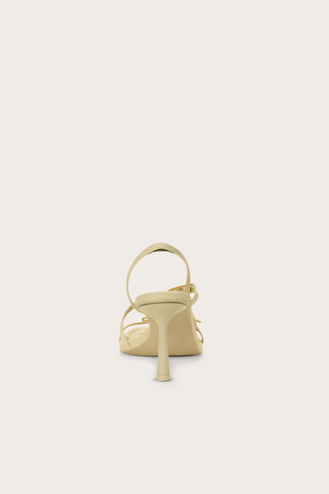 Back view of a cream strappy heel that features two gold buckles and a slingback strap. 