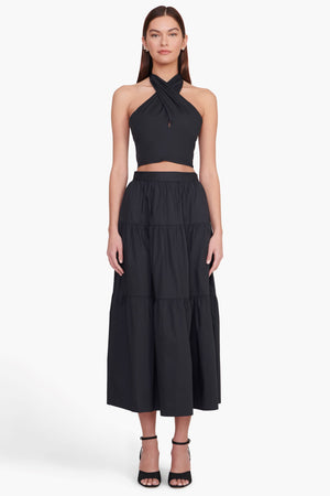 Model facing the camera in the black tiered midi skirt with a matching top