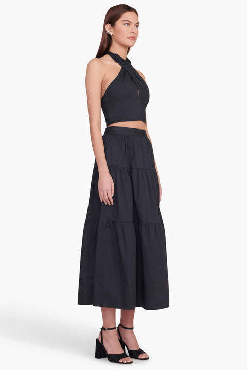 Model turned towards the right in the black tiered midi skirt