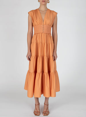 Model wearing the antara a-line midi dress in orange with smocking at the waist.