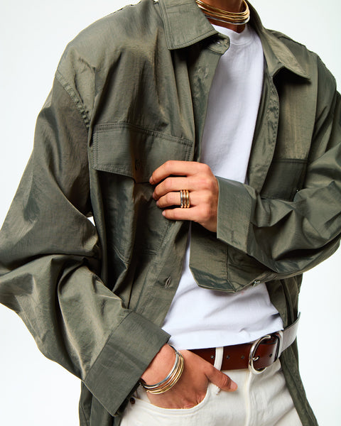 Woman wearing two gold-toned, tubular collar necklaces along with other jewelry. 