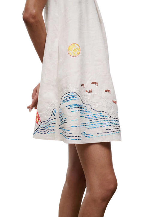 A close-up of a woman wearing a mini dress with embroidered beach details 