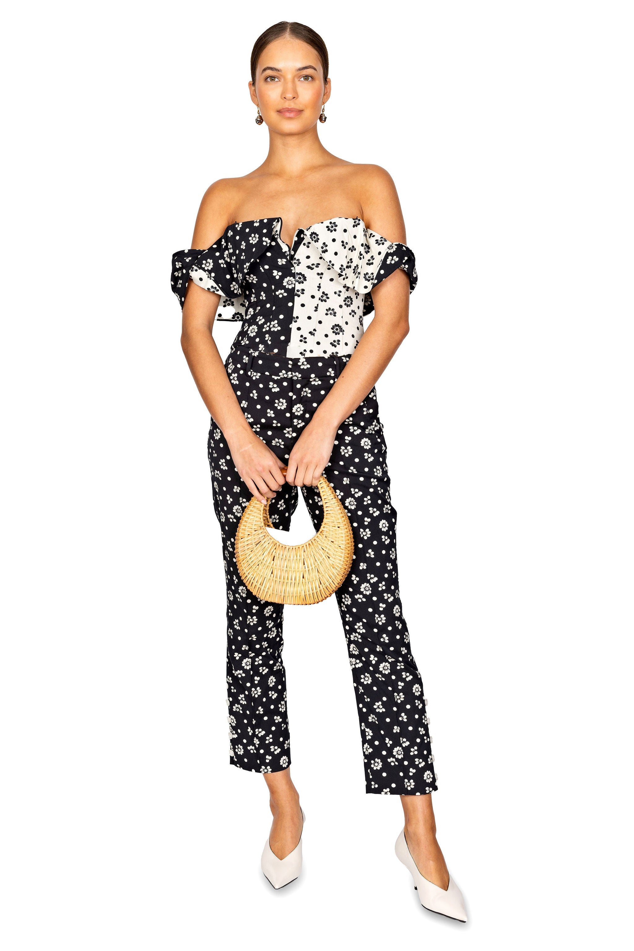 Model styled wearing the black and cream flat around the edges off the shoulder top with a round wicker handbag.