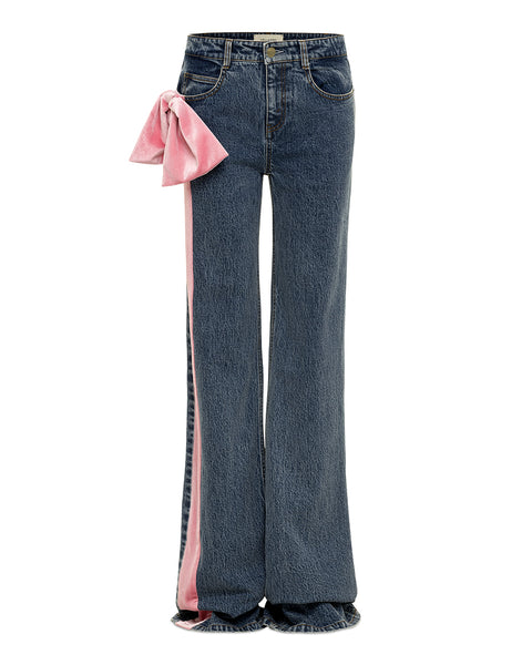 Blue jeans with a pink velvet bow on the right hip and pink velvet stripe down right leg on a white background