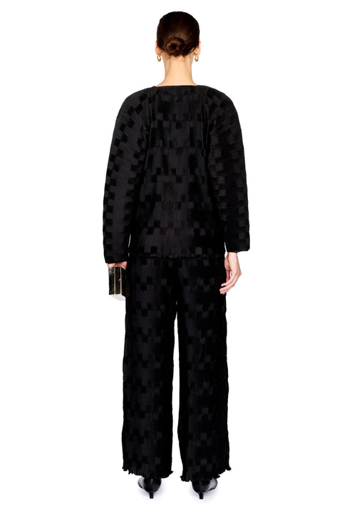 A model shown from the back wearing a black textured two piece set with a subtle geometric pattern, set against a plain white background.