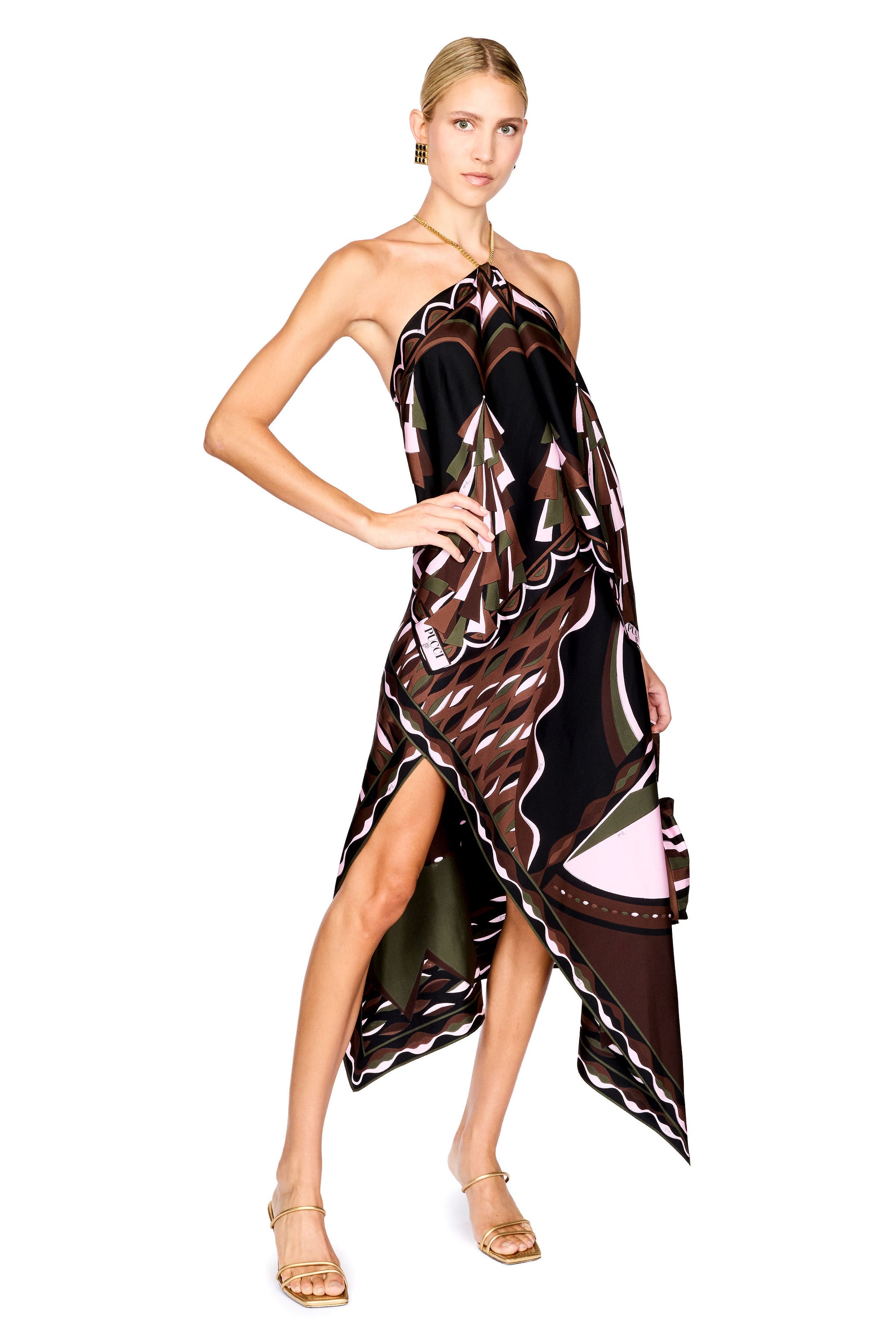 A model wearing a halter-neck, asymmetrical top and midi skirt with a brown, black, and pink abstract pattern, holding a matching handbag against a white background.