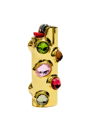 A gold-colored lighter featuring faceted gemstones in green, pink, red, and clear, set against a plain white background.