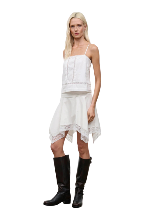 A woman wearing a white lace midi skirt with a matching white sleeveless top side angle