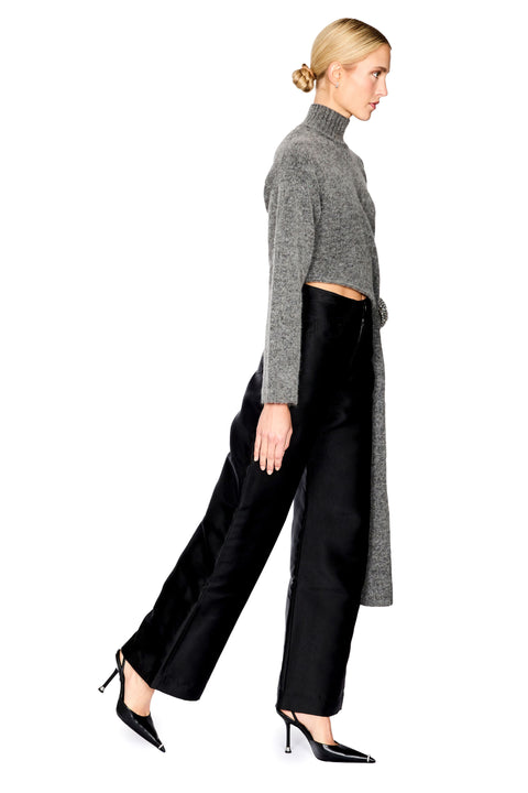 A woman modeling a gray knit mock-neck long-sleeve crop top paired with black wide-leg trousers and black pointed-toe heels, shown in profile against a solid white background.