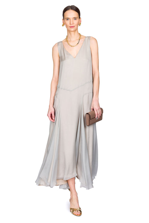 Woman wearing a light gray sleeveless dress holding a clutch on a white background