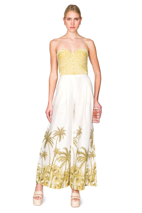 Strapless green bustier top with white piping and white linen palazzo pants with palm tree patterning