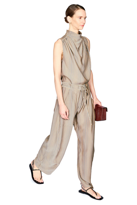 A model stands against a white background wearing a sleeveless, high-neck top and matching pants in a beige and brown vertical stripe pattern. The pant features a gathered waist with a matching fabric tie belt and wide-leg trousers.