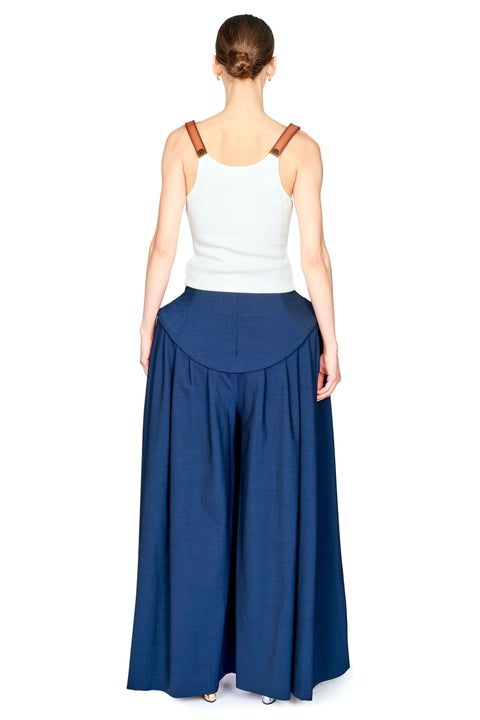 A woman shown from the back wearing a white ribbed tank top with brown shoulder straps and navy blue wide-leg pants, photographed against a plain white background.