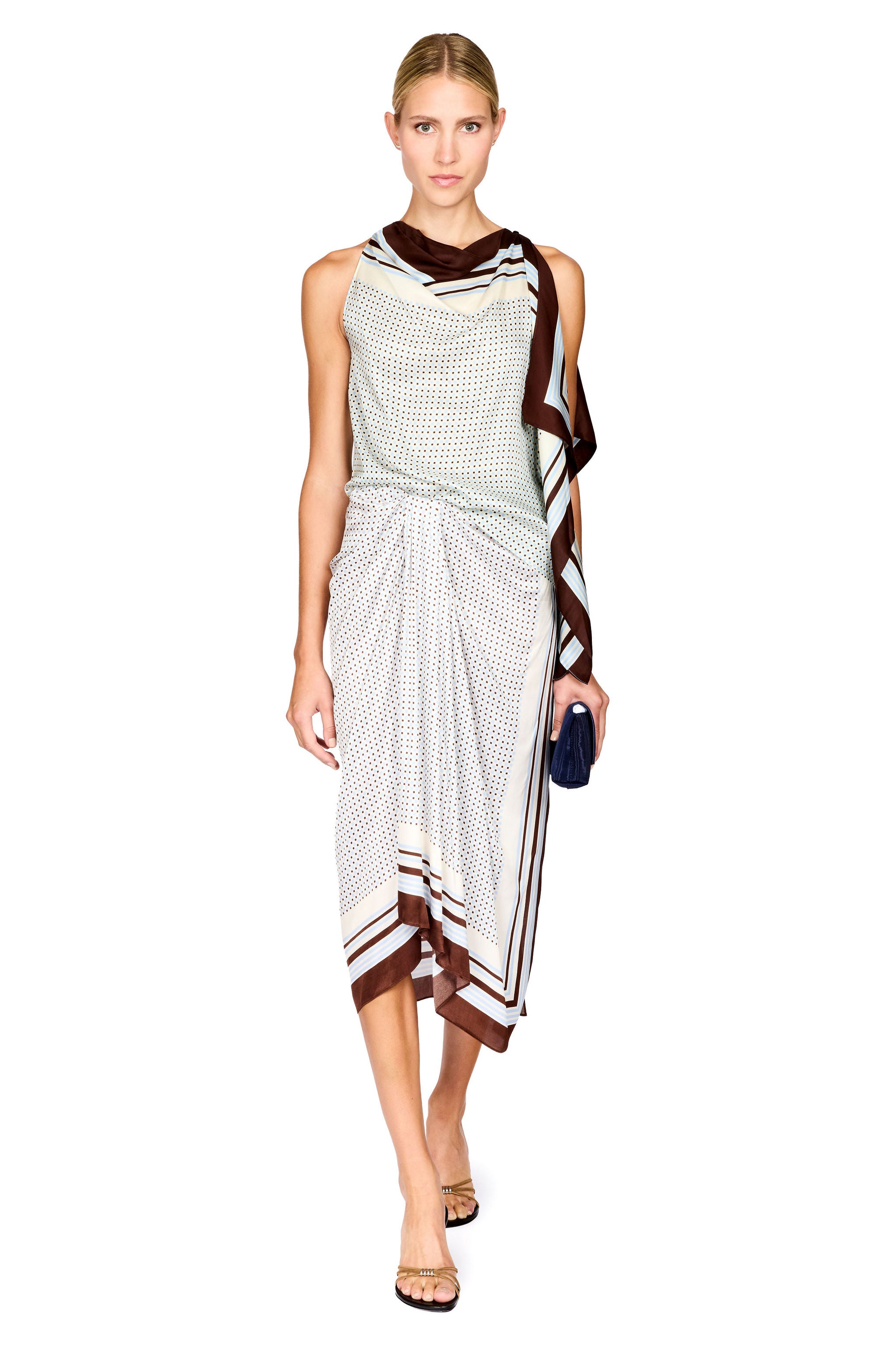 A model wearing a sleeveless scarf-style matching skirt set with a white and brown geometric pattern, styled with a small dark blue clutch, set against a plain white background.
