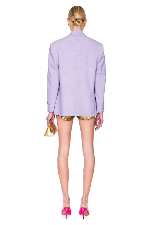 Back-facing woman wearing a light purple blazer with embellishments on a white background.