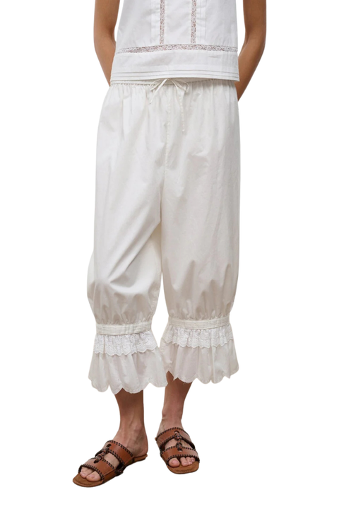 A woman wearing ivory bubble cropped trousers with an embroidered lace hem