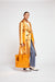 Model turned to the side in the metallic orange trench coat