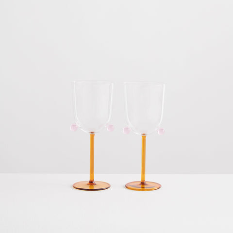 Two Maison Balzac wine glasses with pink pompom detail.