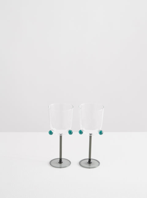 Two Maison Balzac wine glasses with teal colored stem and pompoms.